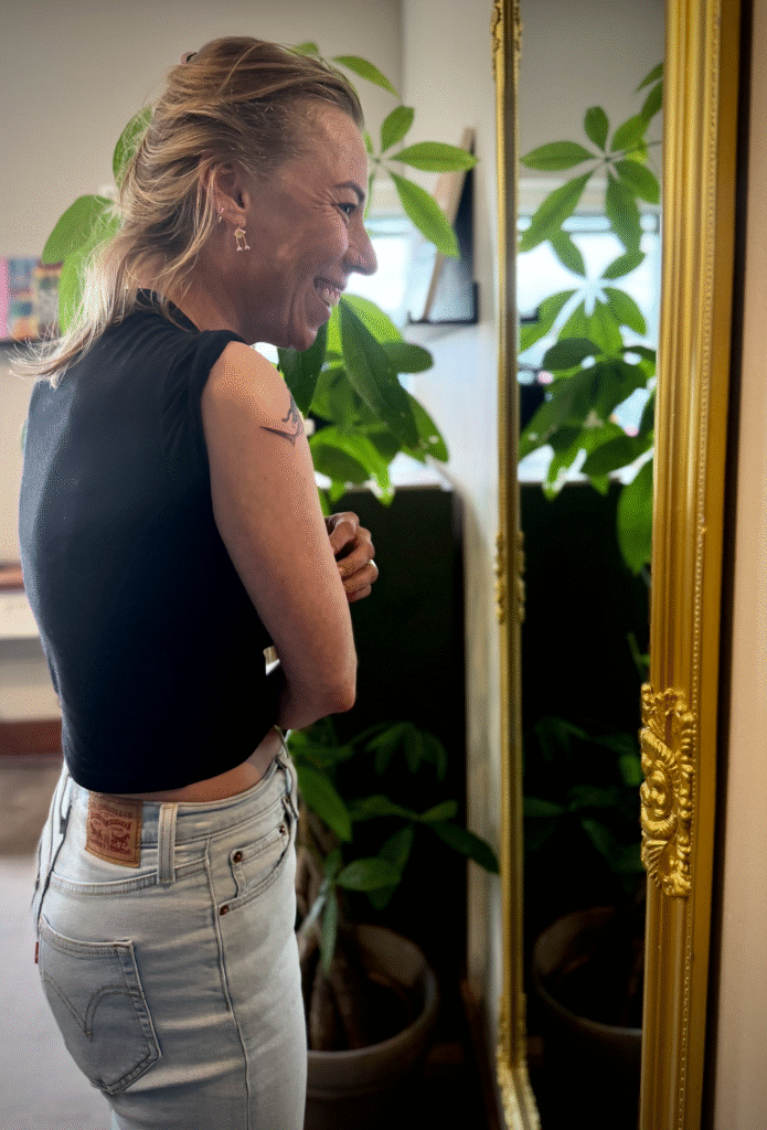 en glad kunde kigger sig i spejlet efter at have fået en tatovering hos Tattoo Ebeltoft